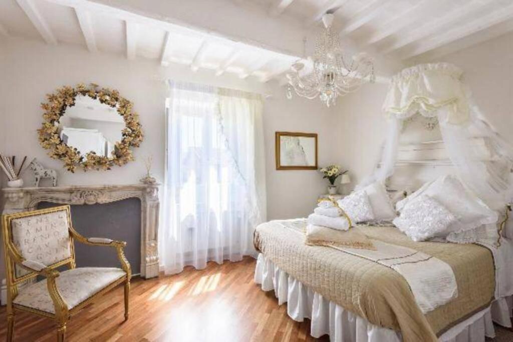 Habitación blanca con cama y lámpara de araña. en Appartamento incantevole nel centro di Arezzo, en Arezzo