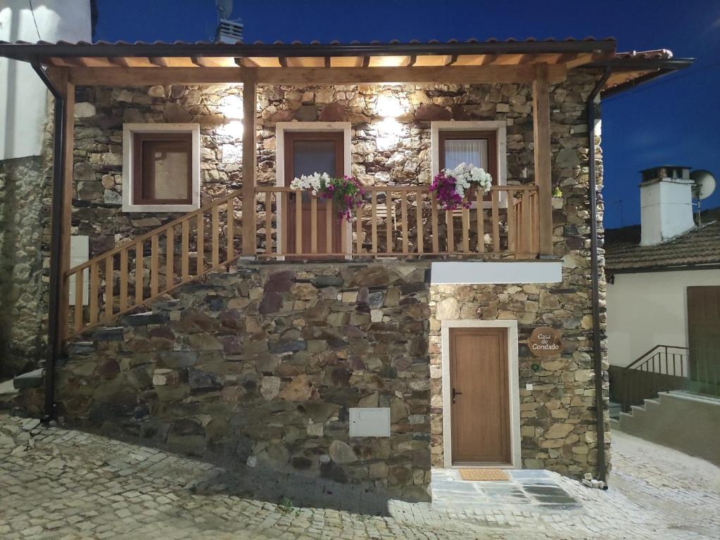 ein Steinhaus mit einem Holzbalkon und einer Treppe in der Unterkunft Casa do Condado in Vilarinho