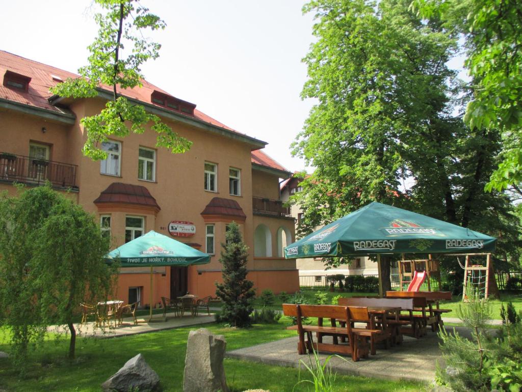 a building with tables and umbrellas in front of it at Penzion - U staré pekárny in Bohumín