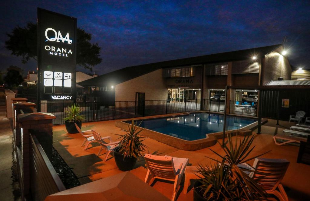 a swimming pool in front of a building at night at Orana Motel in Dubbo