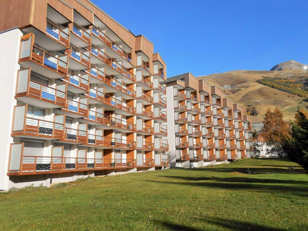 a large apartment building with a grass field next to it at Appartement Les Deux Alpes, 2 pièces, 4 personnes - FR-1-516-43 in Les Deux Alpes