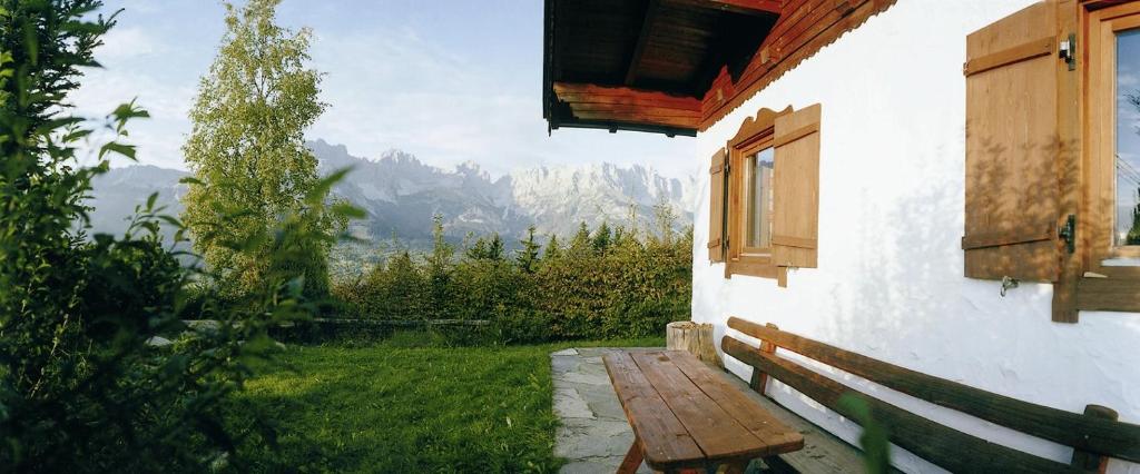 a wooden bench next to a building with a window at Ferienhaus Soregina in Ellmau