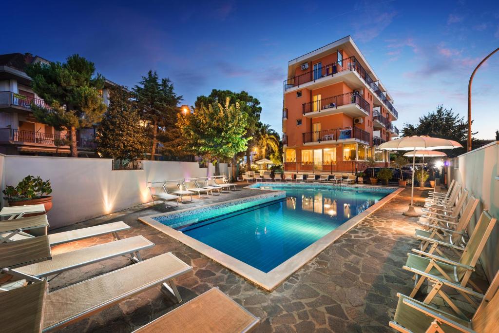 una piscina con sillas y un edificio en Hotel Fenix, en San Benedetto del Tronto