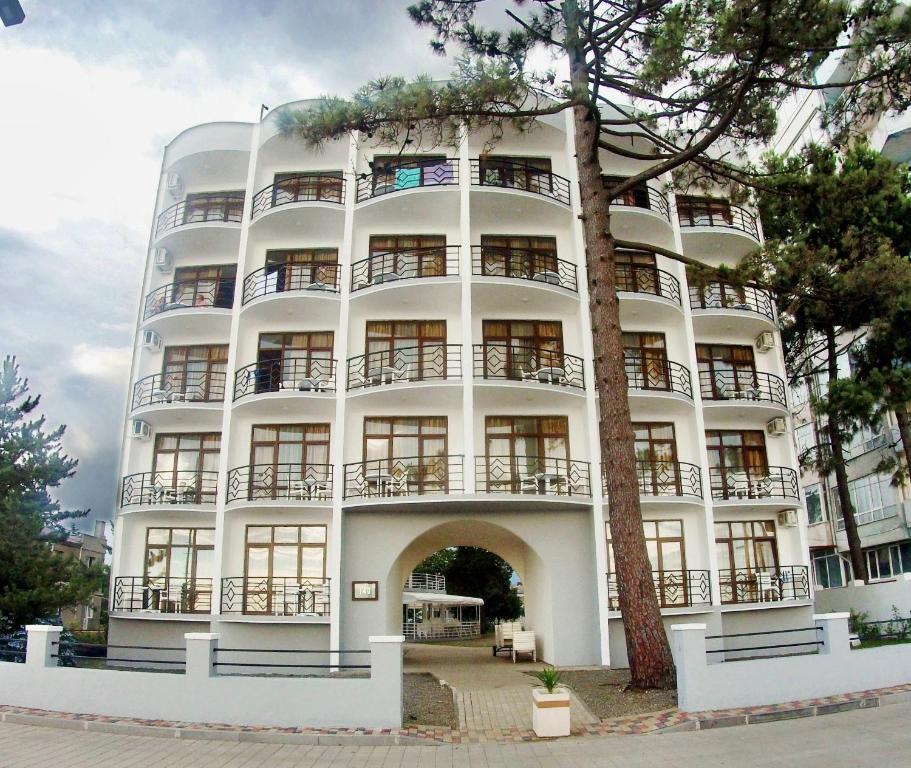 un edificio blanco con un árbol delante en Hotel Medusa, en Kobuleti
