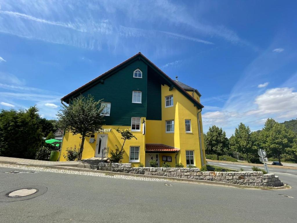 ein gelbes und grünes Haus am Straßenrand in der Unterkunft Landgasthaus Zander in Blankenburg