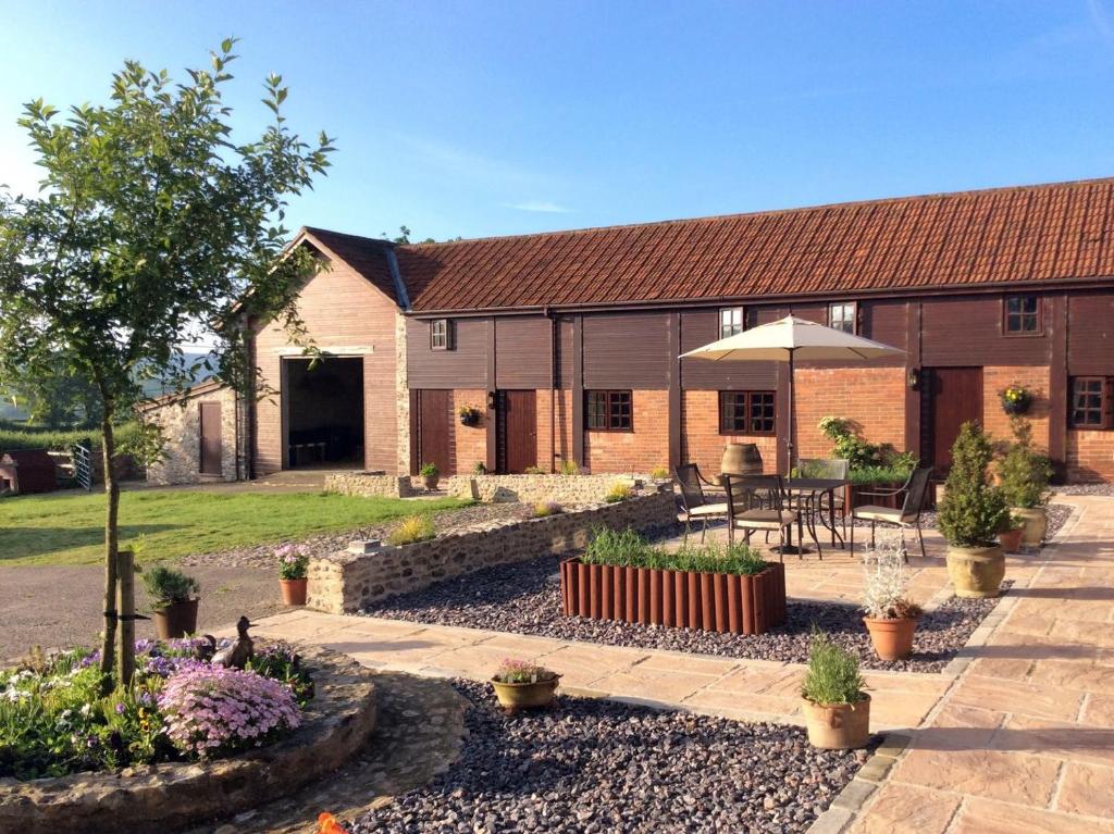 a house with a courtyard with a table and an umbrella at The Linney in Northleigh