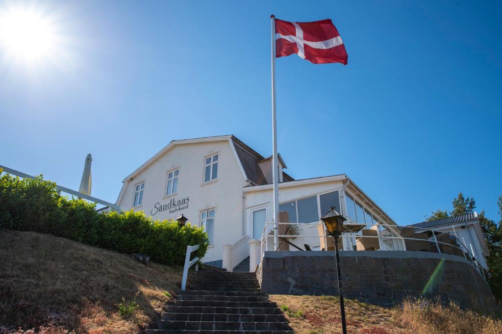 eine Flagge vor einem weißen Gebäude in der Unterkunft Sandkaas Badehotel in Allinge