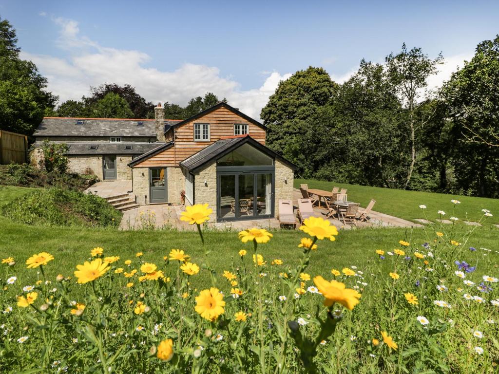 a field of yellow flowers in front of a house at Hillside Cottage in Shaftesbury