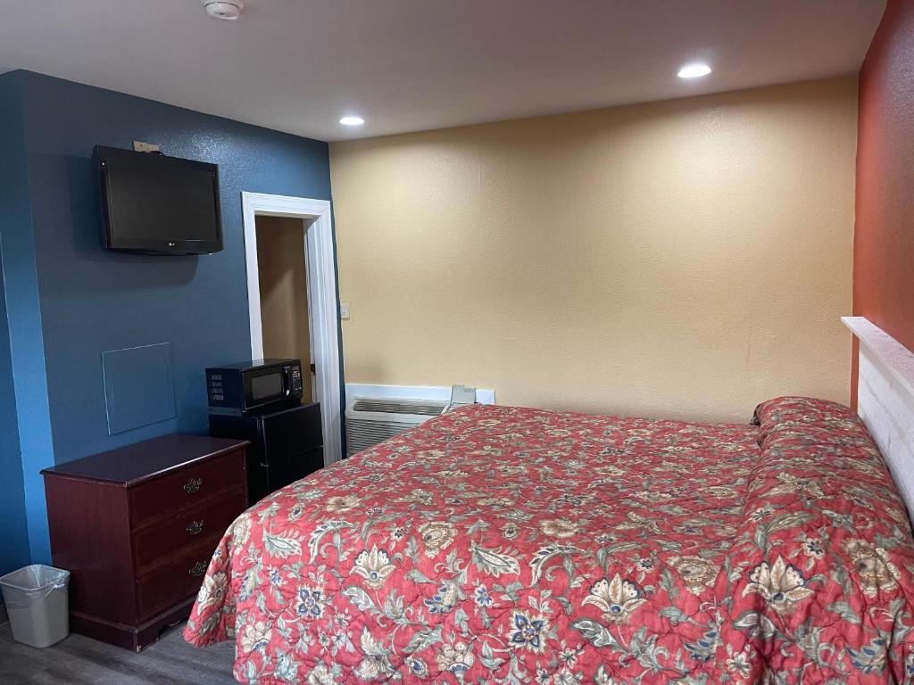 a bedroom with a bed and a flat screen tv at Kenwood Court Motel in Wilson