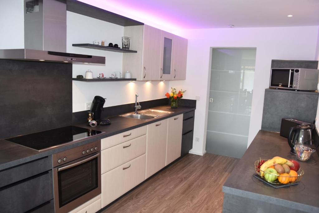 a kitchen with white cabinets and a bowl of fruit on the counter at Top-Moderne und geräumige Ferienwohnung in Aßling