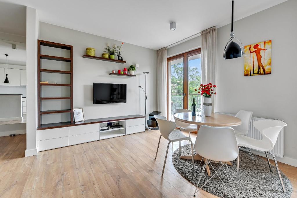 sala de estar con mesa, sillas y TV en Luxury Bianco Apartament, en Sopot