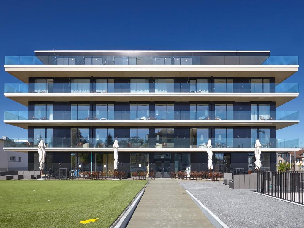 a large building with a lawn in front of it at Hotel AVA in Sempach Station