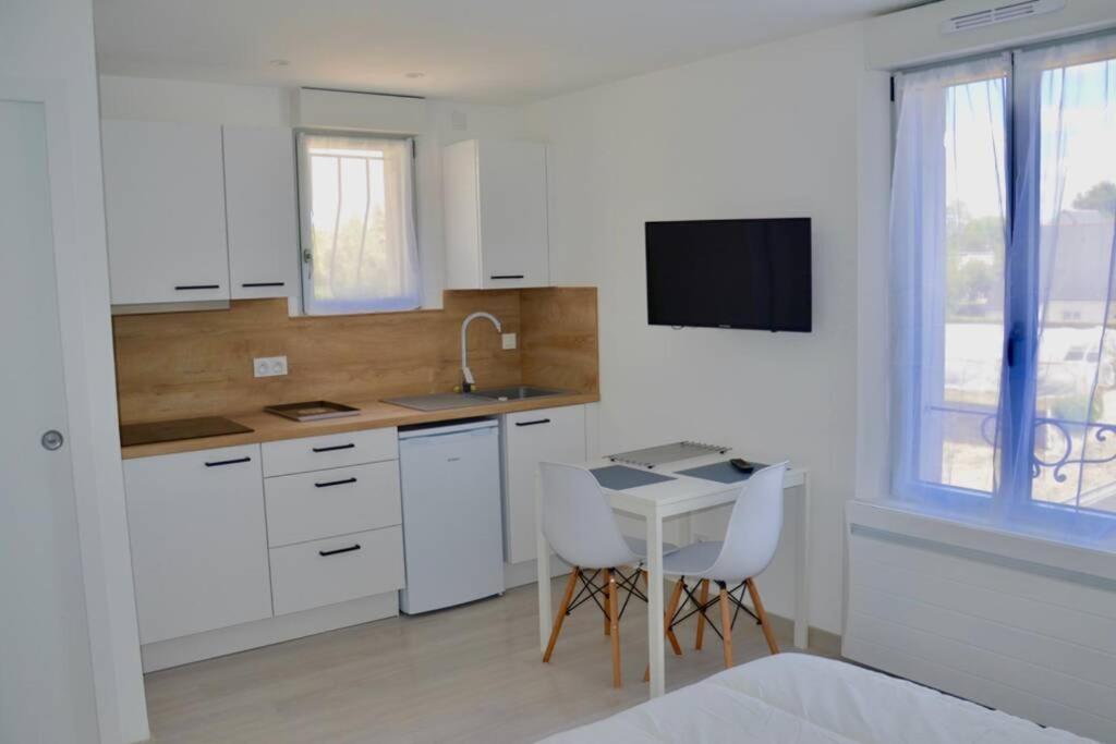 a kitchen with white cabinets and a table and a tv at Les Forges studio étage in Avoine