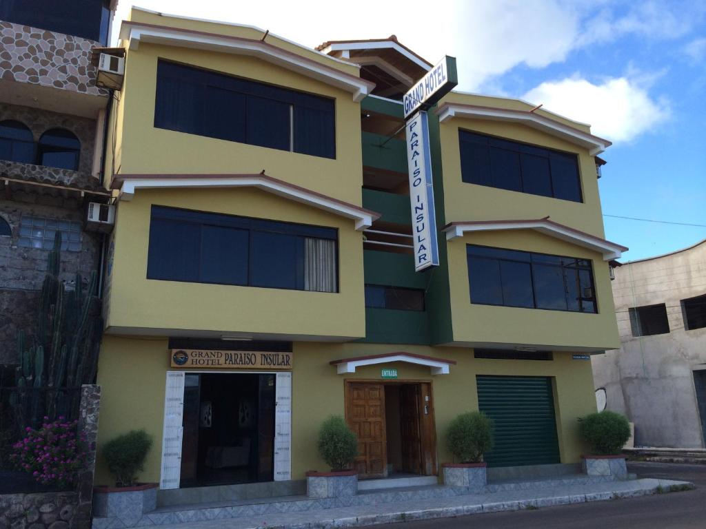 um edifício amarelo com um sinal em frente em Grand Hotel Paraiso Insular 1 em Puerto Baquerizo Moreno