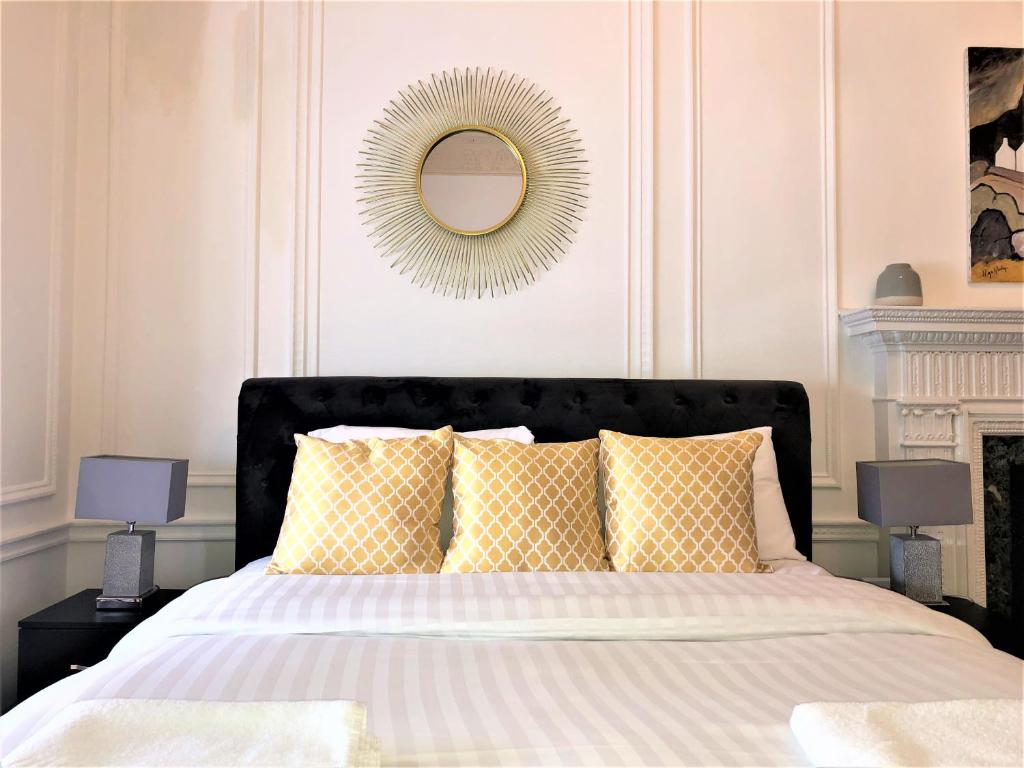 a bedroom with a bed with yellow pillows and a mirror at The Courtfield Plaza in London