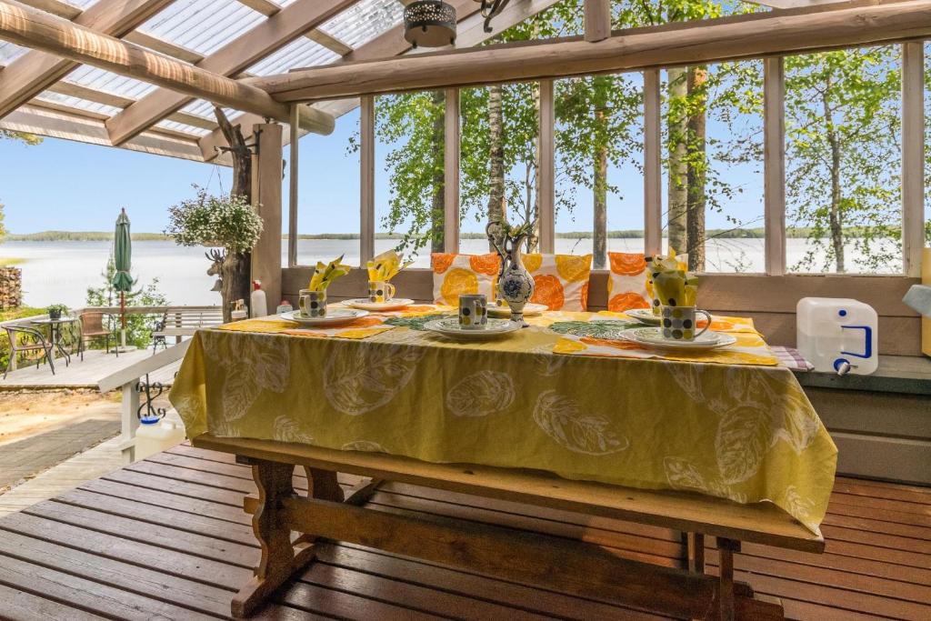 uma mesa com uma toalha de mesa amarela num deque em Upea hiekkaranta mökki em Ahtari