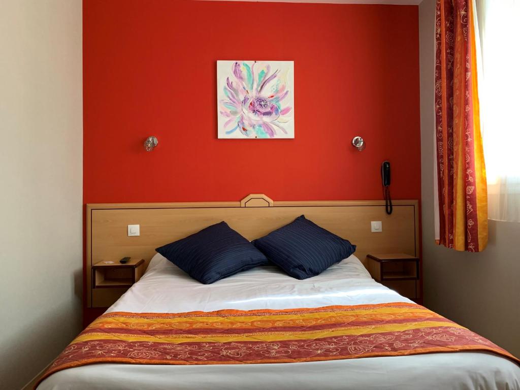 a bedroom with a bed with a red wall at Hotel du Haut Marais in Saint-Marcel