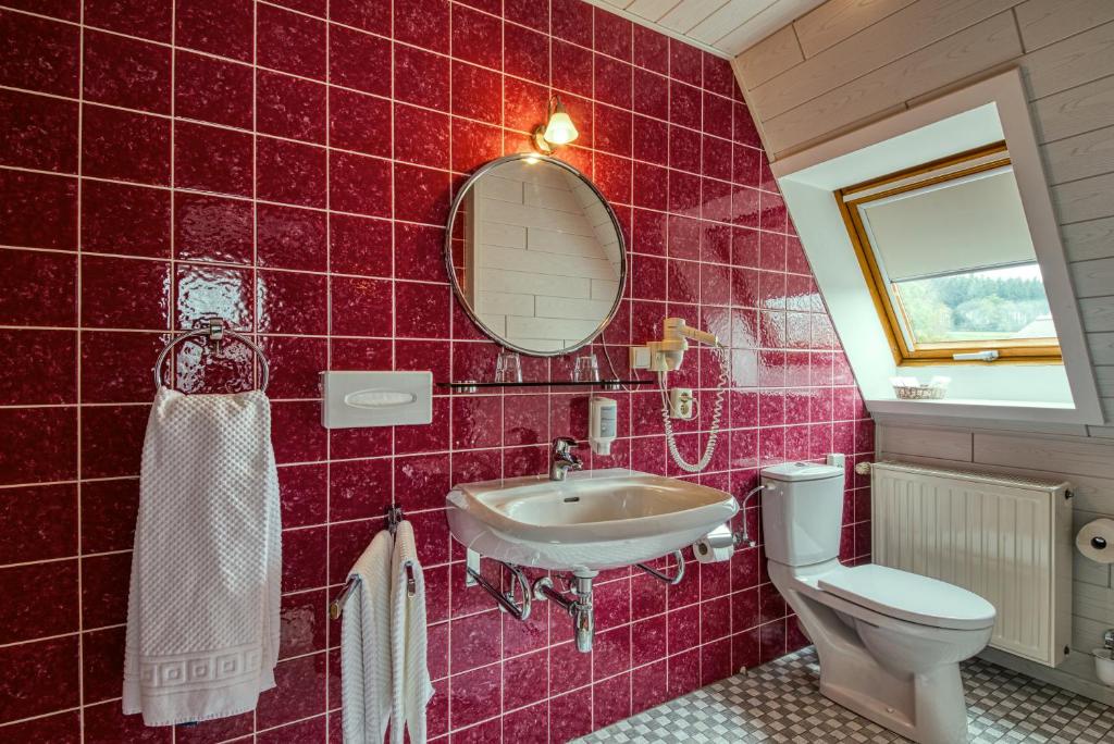 a red tiled bathroom with a sink and a toilet at Hotel Haus Tiefenbach in Bullange