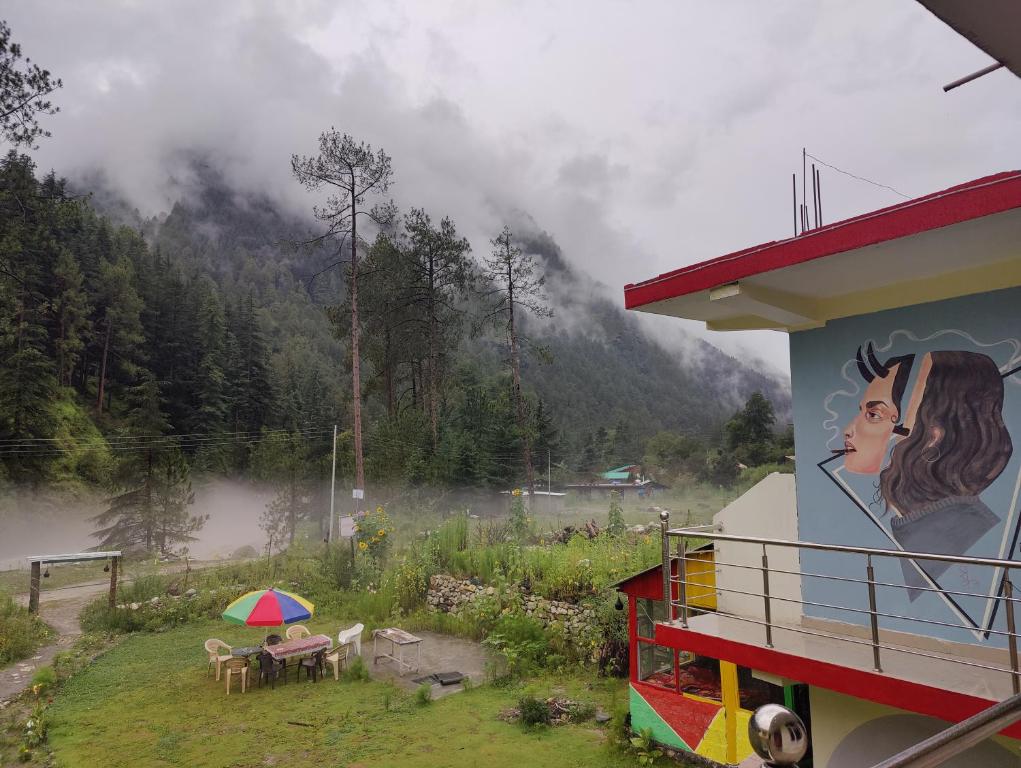 a mural on the side of a building with a view of a mountain at Breathe Inn in Kasol