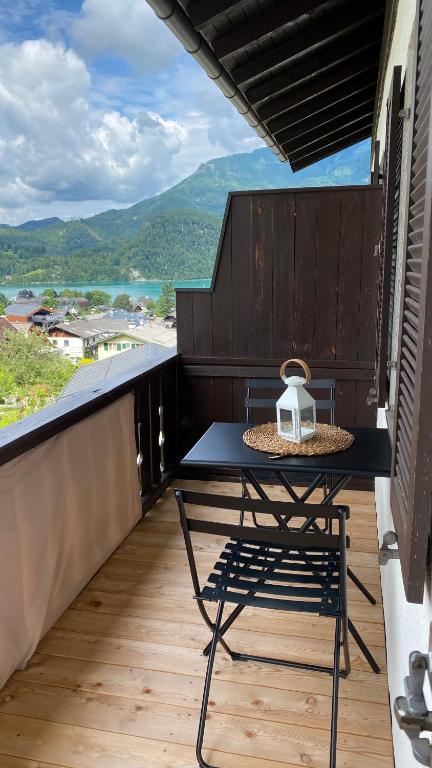a table and a chair on a balcony with a view at Seeblick Apartment in Sankt Gilgen