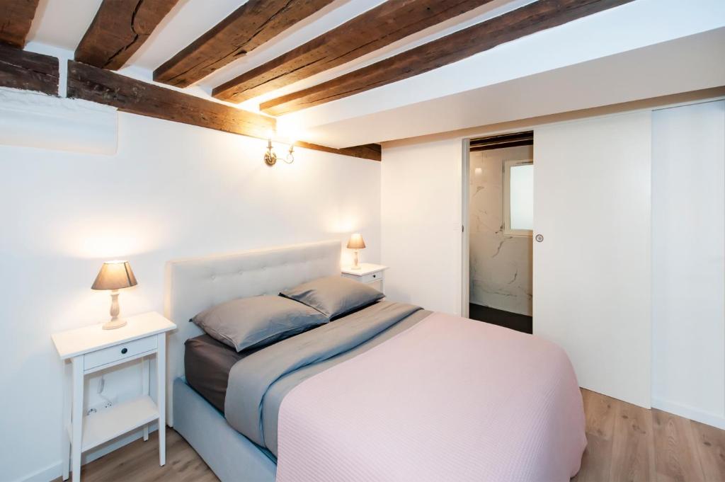 a white bedroom with a bed and a nightstand at Paris Place du Pantheon in Paris