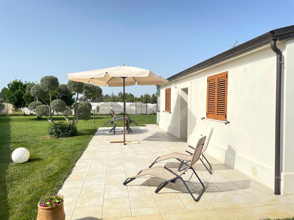 a patio with two chairs and an umbrella at Villetta al mare Scanzano Jonico in Scanzano