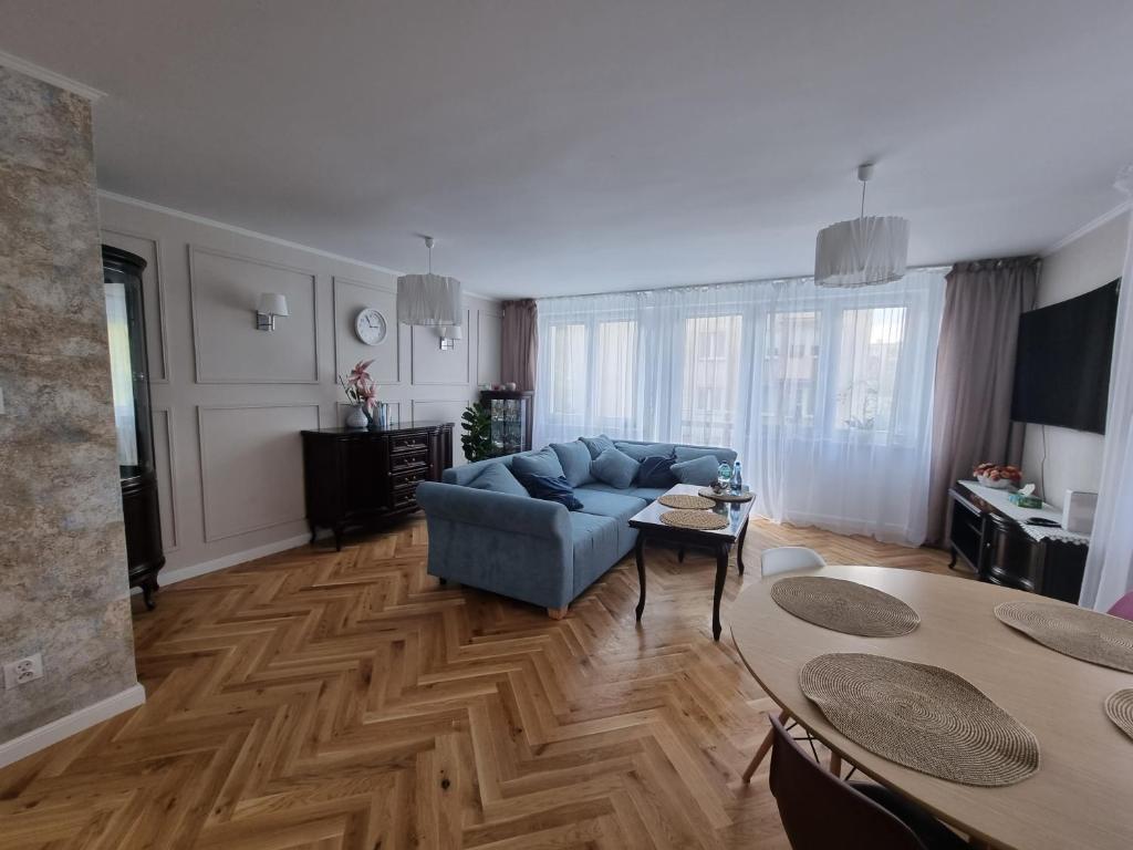 a living room with a blue couch and a table at Apartament Józefa Bema - Gdynia Śródmieście in Gdynia