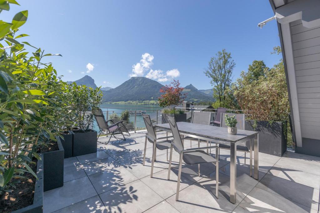 a table and chairs on a patio with a view of the water at SEE & The City in St. Wolfgang