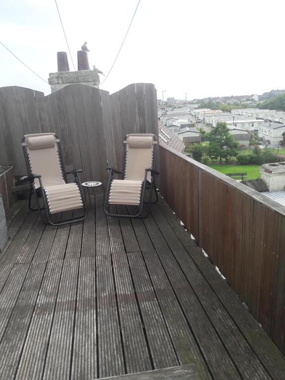 trois chaises assises sur une terrasse avec une clôture dans l'établissement Het Populierennest, à Middelkerke