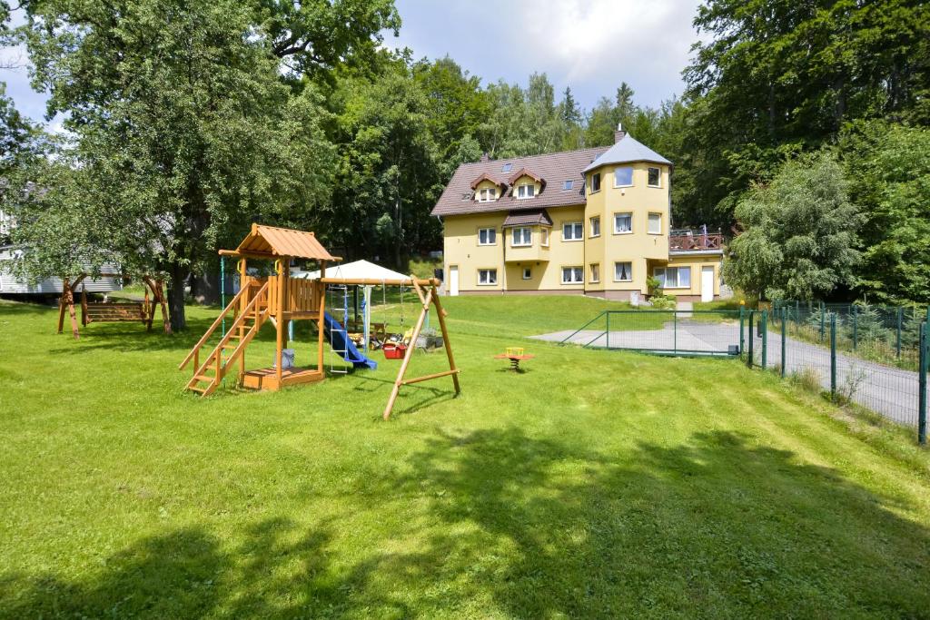 um quintal com um parque infantil com uma casa ao fundo em Słoneczny Domek em Szklarska Poręba