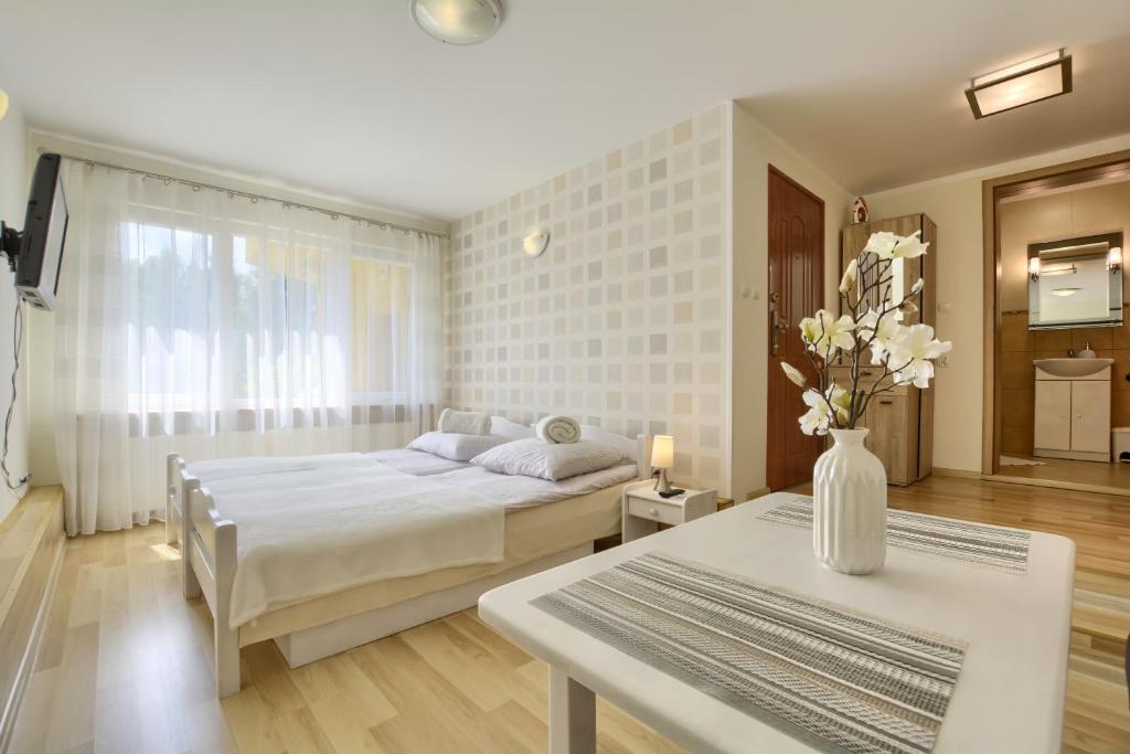 ein Schlafzimmer mit einem Bett und einem Tisch mit einer Blumenvase in der Unterkunft Słoneczny Domek in Szklarska Poręba