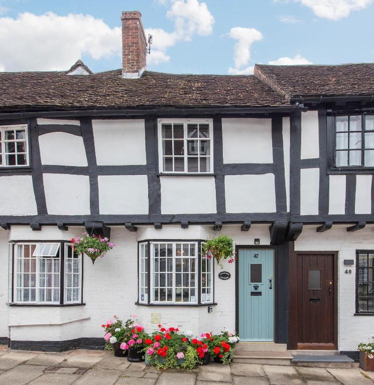 a black and white house with flowers in front of it at Charlie's Cottage in Ludlow