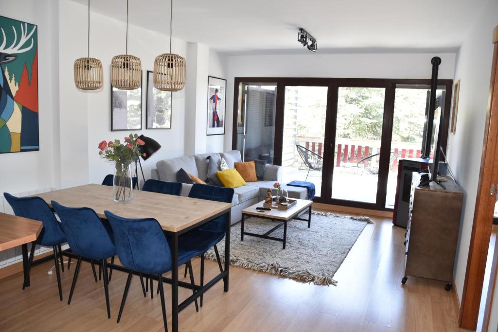 a living room with a table and blue chairs at Apartamento Plaza de Pradollano - Parking incluido in Sierra Nevada