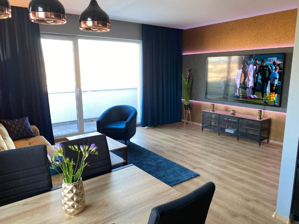 a living room with a tv and a couch and chairs at VIP Apartament-Marine in Rumia