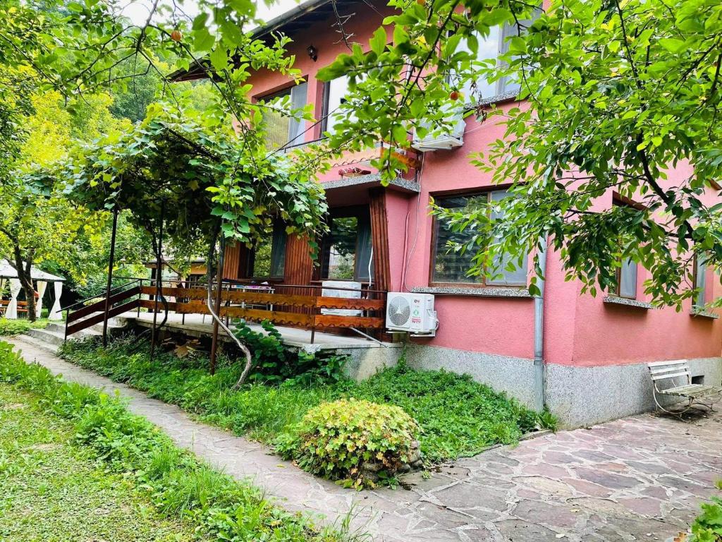 une maison rose avec un banc devant elle dans l'établissement Къща за гости Станеви, à Ribarica