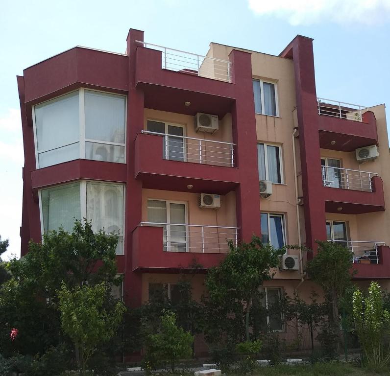 a red building with balconies on the side of it at Акротирия Фешева in Nesebar