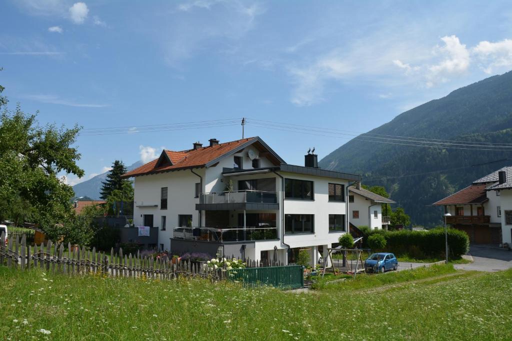 a house on a hill with mountains in the background at Apart Pitztalurlaub in Wenns