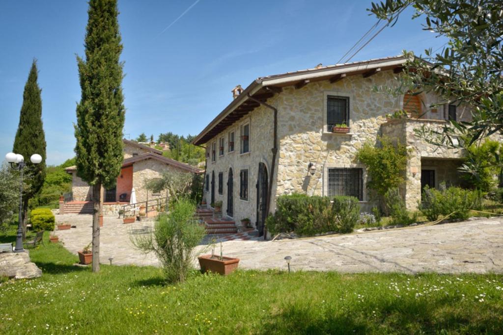 uma antiga casa de pedra com um jardim em frente em Il Casale Delle Ginestre em Castel San Pietro Romano