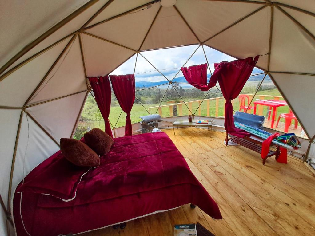 a bedroom in a tent with a bed and a chair at Skyline Glamping Guasca in Guasca