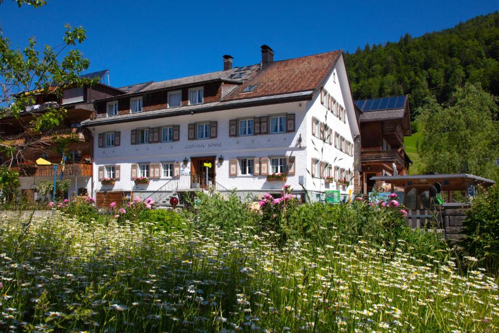 ein Haus in den Bergen mit einem Blumenfeld in der Unterkunft Sonne Bezau - Familotel Bregenzerwald in Bezau