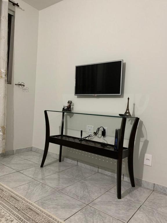 uma televisão numa parede branca com um banco num quarto em Apartamento bem localizado próximo ao DETRAN, Assembleia Legislativa de Cuiabá, Centro Político e Shopping Pantanal em Cuiabá