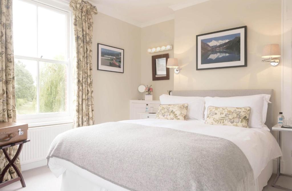 um quarto com uma grande cama branca e uma janela em Saddlers B&B em Funtington
