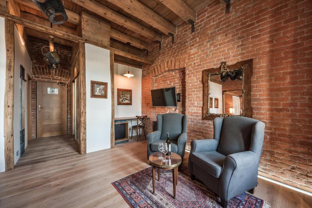 duas cadeiras e uma mesa num quarto com uma parede de tijolos em Hotel Mariánský Dvůr em Uherské Hradiště