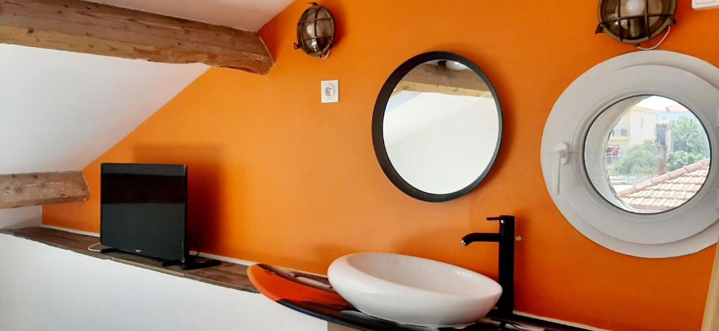 an orange bathroom with a sink and two windows at Le Paddle - station balnéaire Les Sablettes in La Seyne-sur-Mer