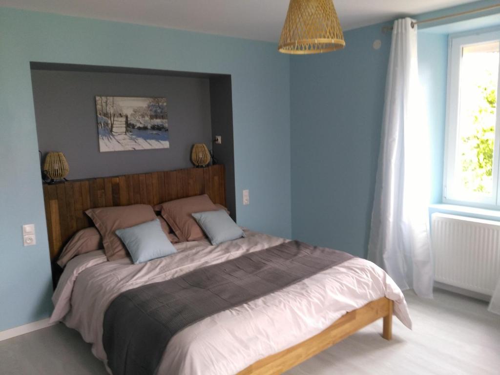 - une chambre avec un grand lit aux murs bleus dans l'établissement Les Chambres d Odile, à Lachapelle-sous-Chaux