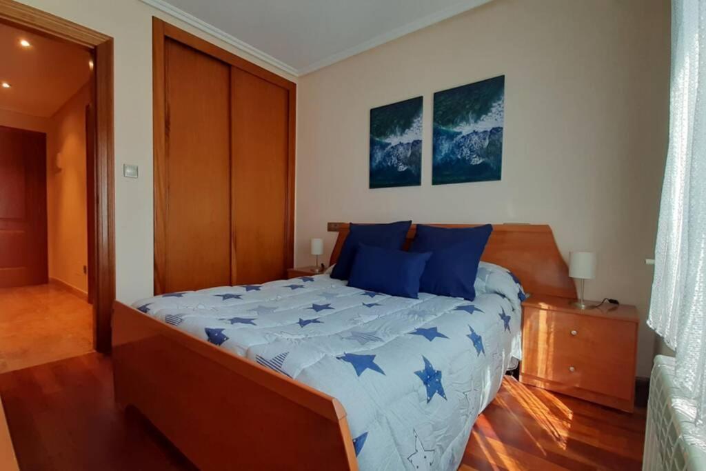 a bedroom with a large bed with blue pillows at Apartamento in Ferrol