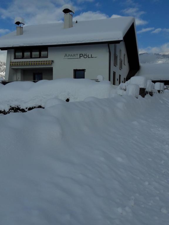 a house covered in snow in front of it at Apart Pöll in Ried im Oberinntal