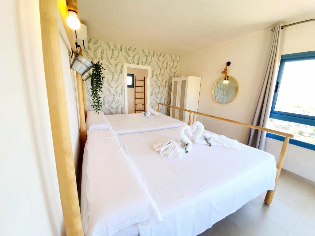 2 camas en una habitación con sábanas blancas en B&B La Nava Suites, en Mojácar
