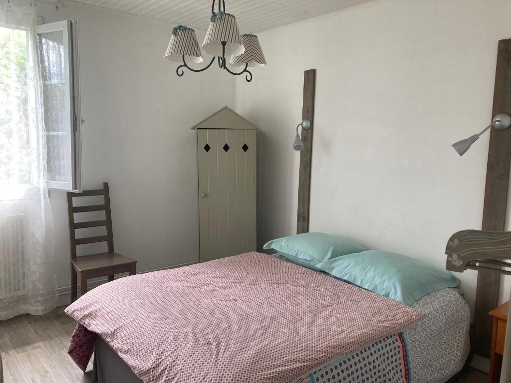 a bedroom with a bed and a chair and a chandelier at Appartement 2/3 personnes à 10 minutes de Contis plage (Saint Julien en Born) in Saint-Julien-en-Born