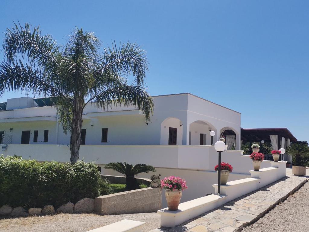 una casa blanca con palmeras delante en Tenuta Turchi, en Otranto
